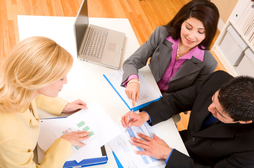 Three business people looking over charts and graphs and discussing a business matter.